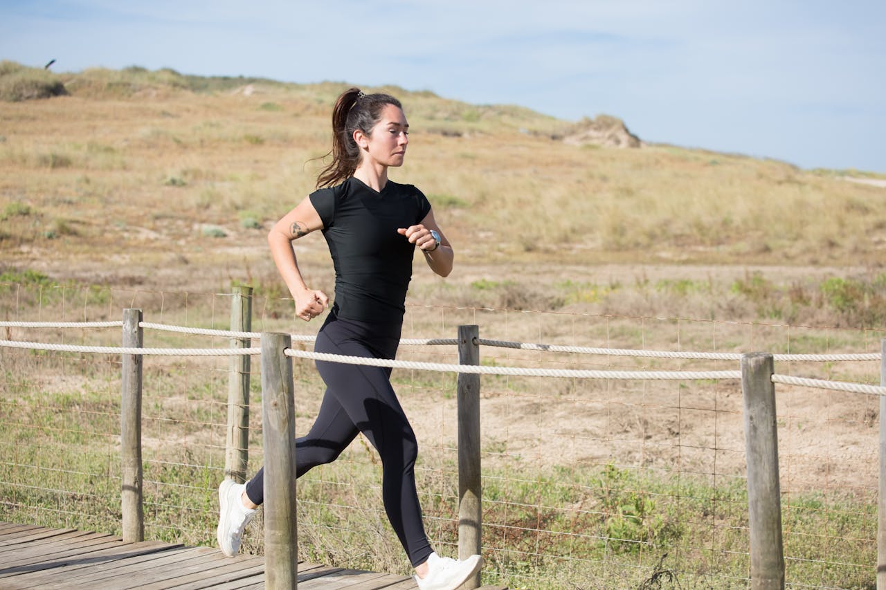 Woman jogging on a sunny day on a wooden path in Portugal, embracing a healthy lifestyle.